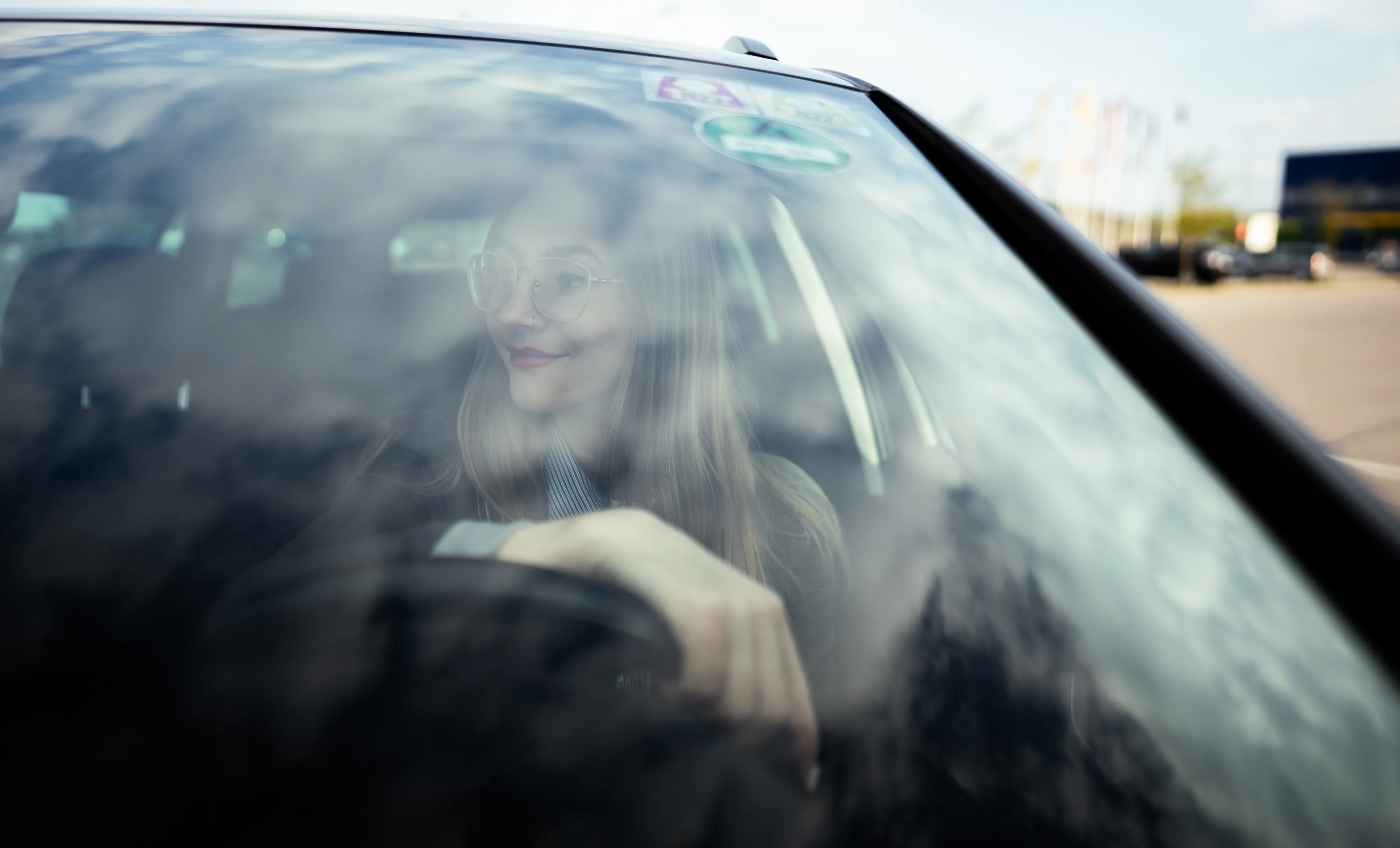 A woman at the wheel of a car, looking out of the window
