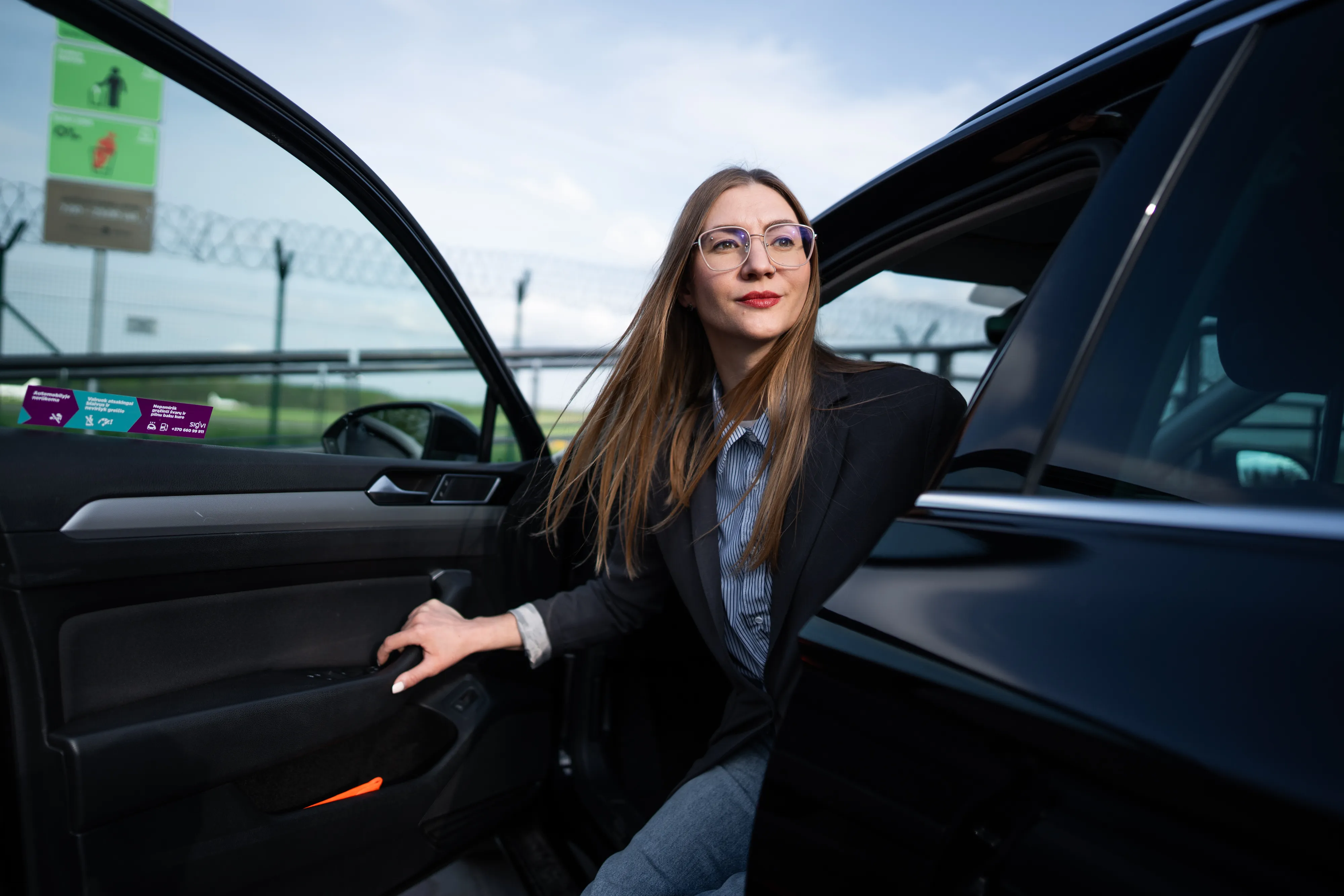 A smiling woman stepping out of a black Sigvi car