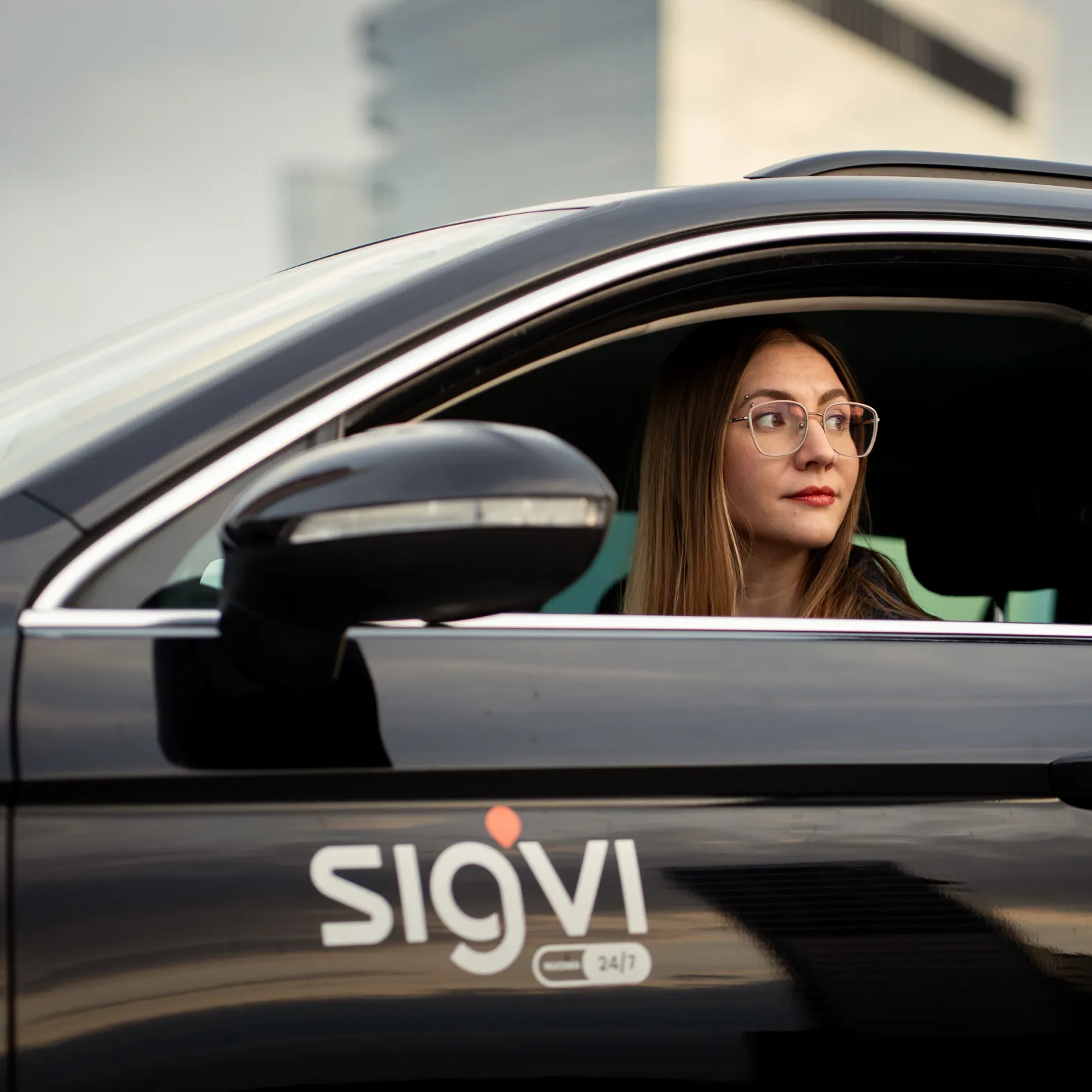 A woman looking out of the window of a Sigvi car