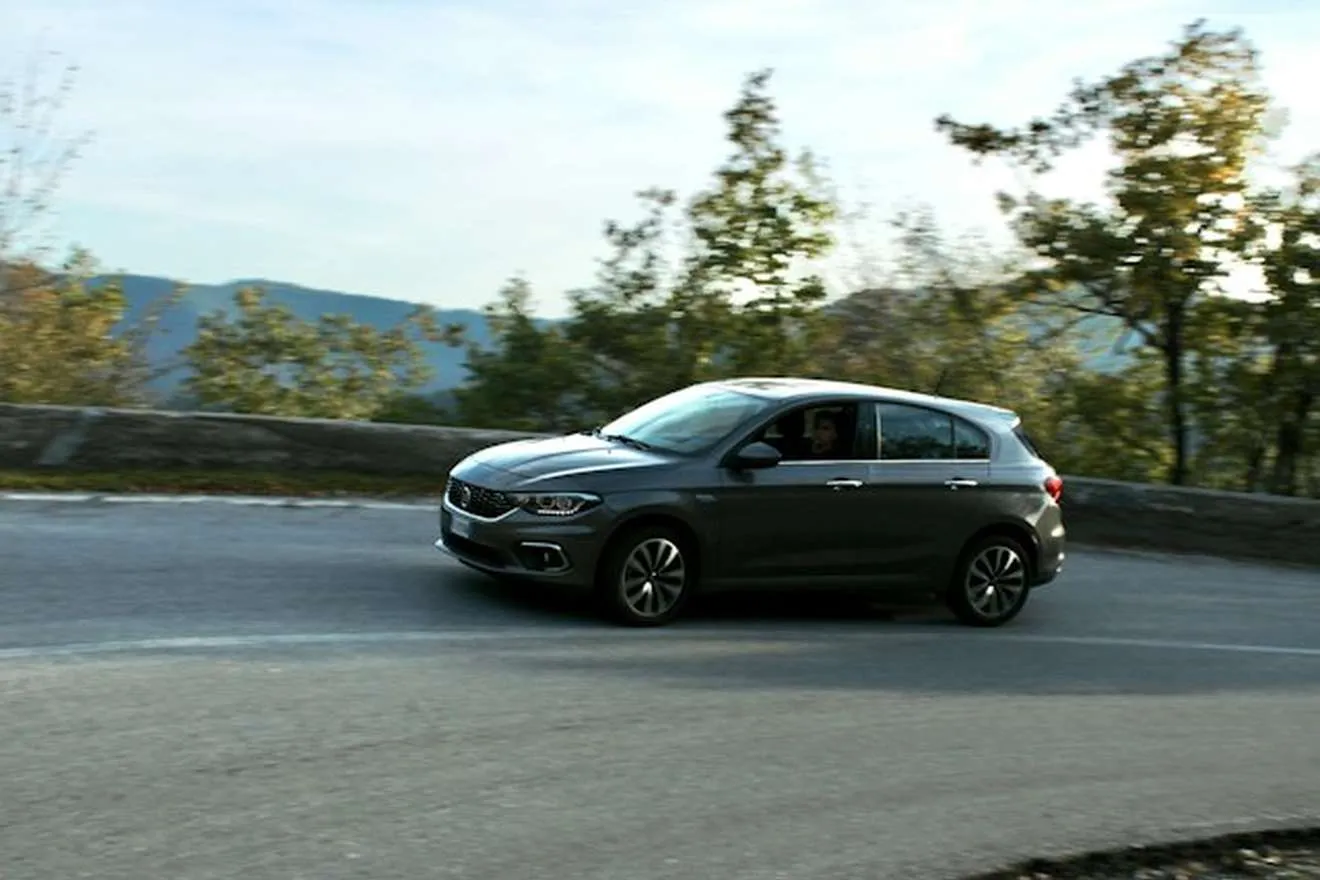 A grey hatchback driving along a mountain road