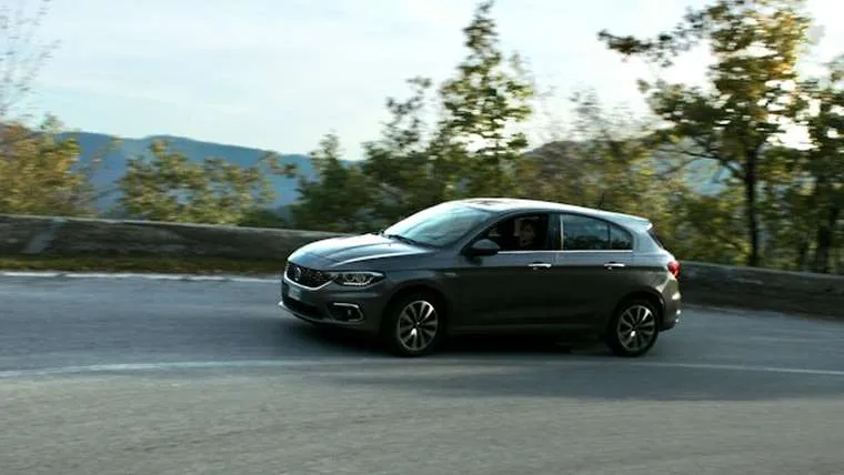 A grey hatchback driving along a mountain road