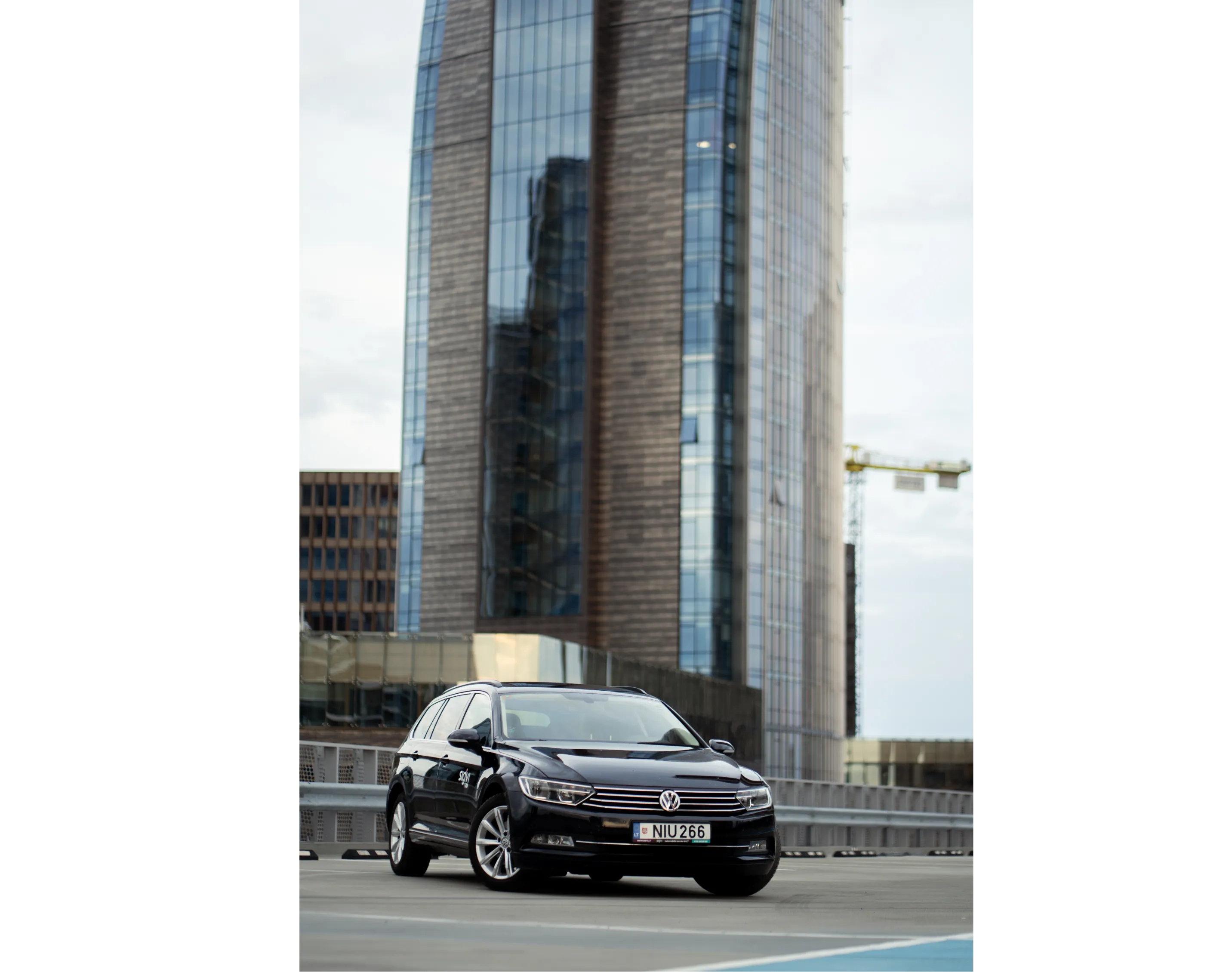 A black Sigvi VW Passat wagon on a city street